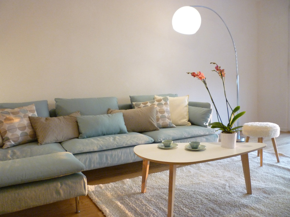 Photo of a mid-sized scandinavian open concept family room in Other with white walls and light hardwood floors.