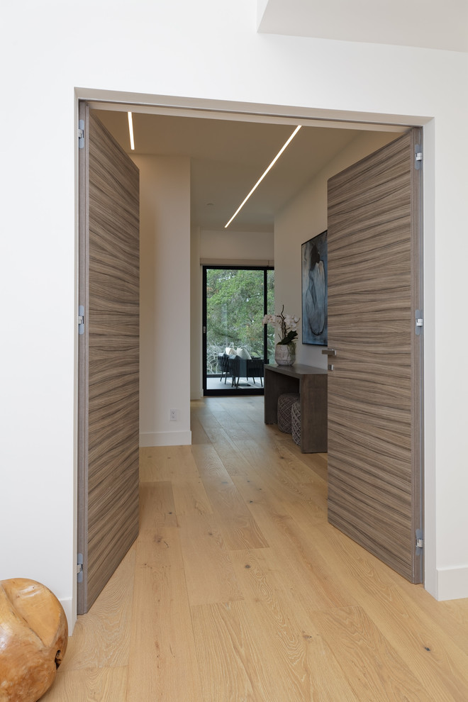 Large modern master bedroom in San Francisco with white walls, light hardwood floors and beige floor.