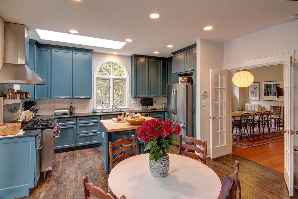 Inspiration for an eclectic u-shaped eat-in kitchen in DC Metro with recessed-panel cabinets, blue cabinets, white splashback, subway tile splashback and stainless steel appliances.