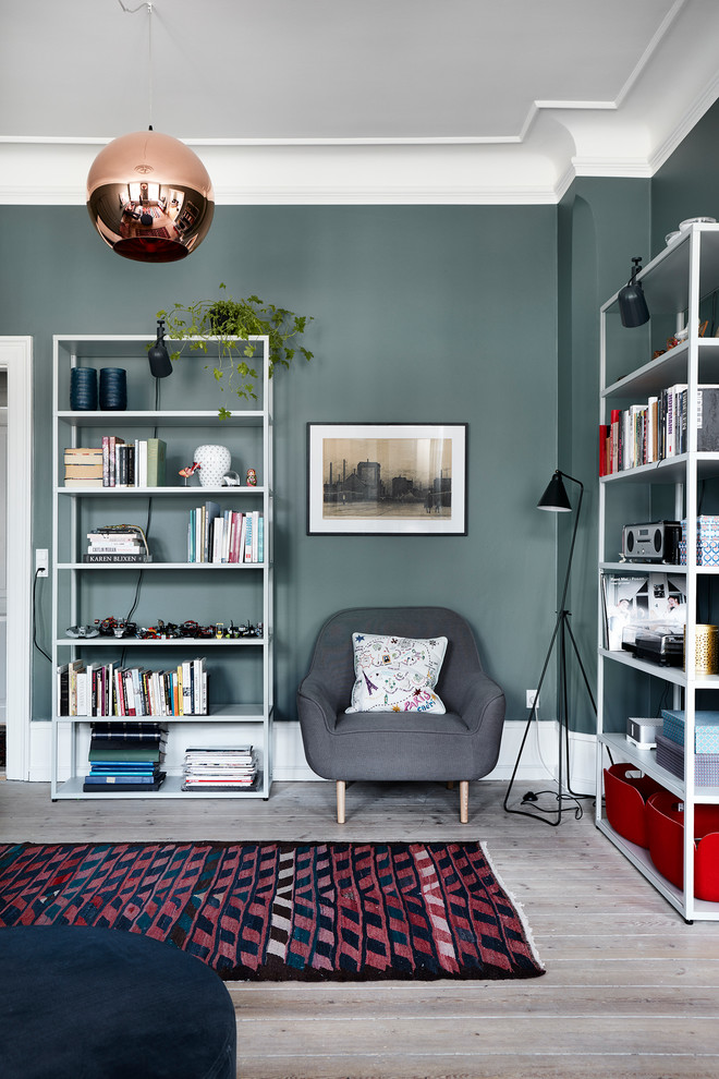 Photo of a mid-sized scandinavian living room in Copenhagen with a library, blue walls, light hardwood floors and beige floor.