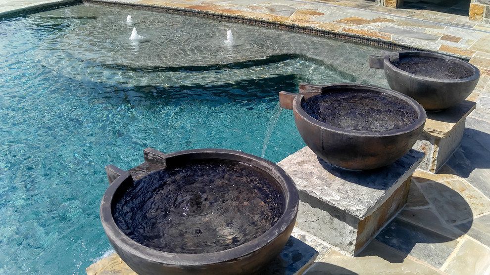 Photo of a large traditional backyard rectangular lap pool in Dallas with a water feature and natural stone pavers.