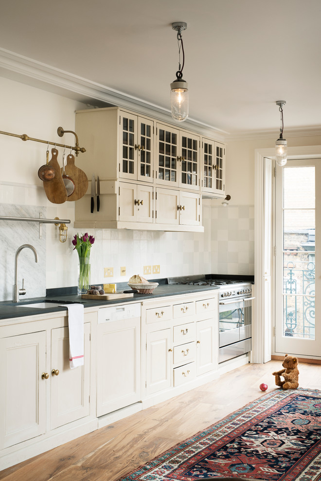 This is an example of a traditional galley open plan kitchen in London with beaded inset cabinets, white cabinets, ceramic splashback, stainless steel appliances and no island.