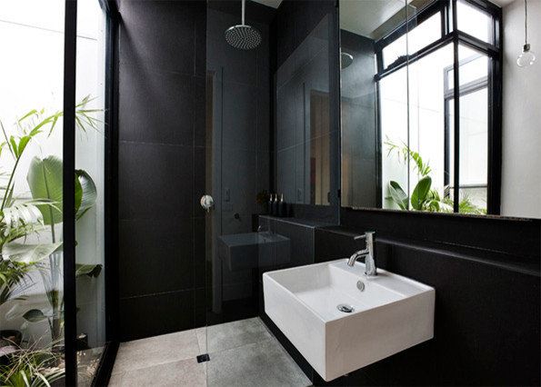 Small contemporary master bathroom in Melbourne with a wall-mount sink, flat-panel cabinets, black cabinets, tile benchtops, an open shower, a one-piece toilet, black tile, ceramic tile, black walls and travertine floors.