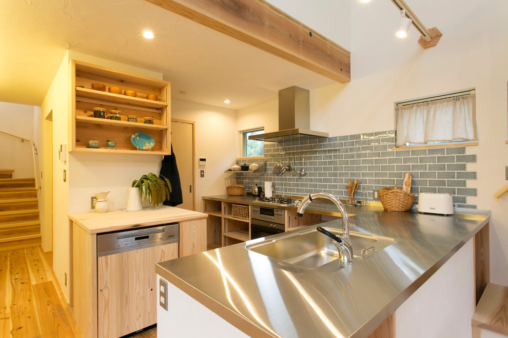 Photo of an asian l-shaped kitchen in Yokohama with a single-bowl sink, open cabinets, stainless steel benchtops, blue splashback, medium hardwood floors and brown floor.