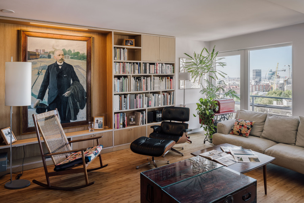 Photo of a large contemporary living room in Madrid with a library, bamboo floors, wood walls, white walls and brown floor.
