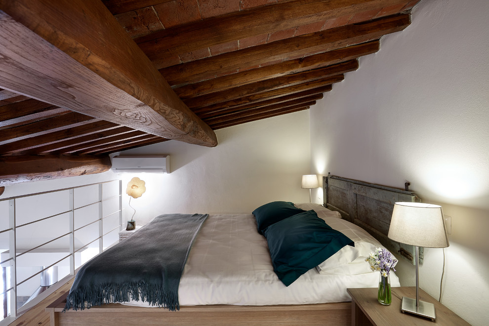 Photo of a small country loft-style bedroom in Florence with white walls, light hardwood floors and beige floor.
