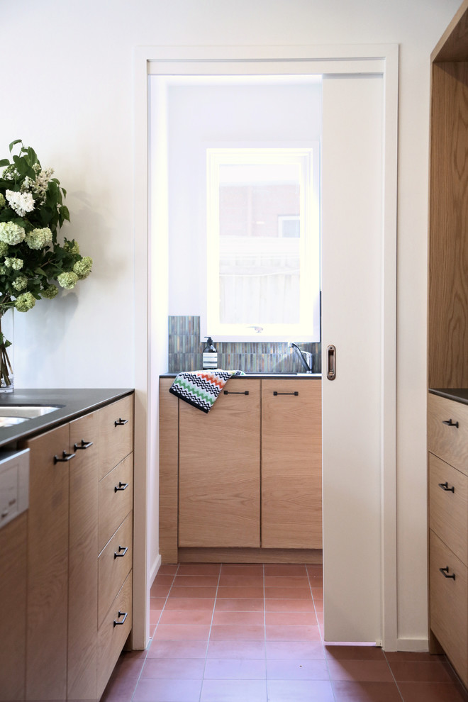 Mid-sized traditional u-shaped kitchen pantry in Melbourne with an undermount sink, flat-panel cabinets, light wood cabinets, green splashback, mosaic tile splashback, stainless steel appliances, ceramic floors and with island.