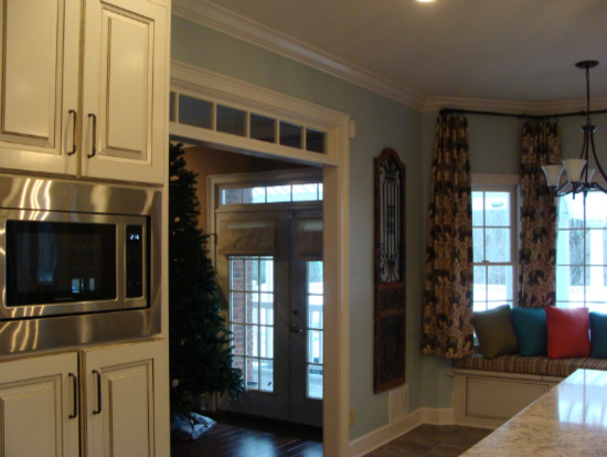 Example of a transitional ceramic tile kitchen design with an undermount sink, raised-panel cabinets, white cabinets, solid surface countertops, subway tile backsplash, stainless steel appliances and an island