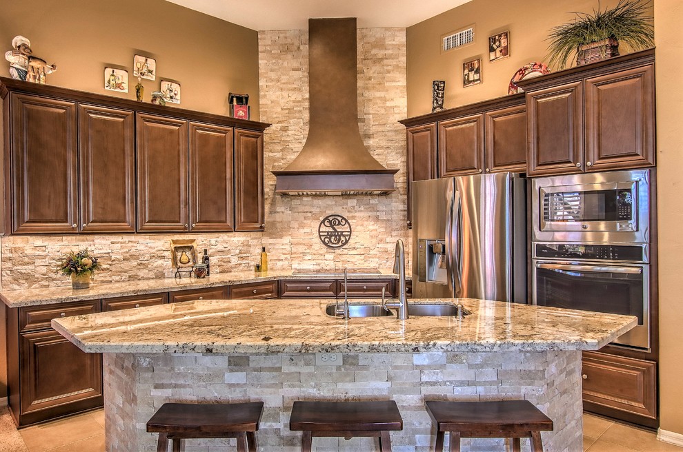 Open concept kitchen - large transitional l-shaped brown floor open concept kitchen idea in Phoenix with a double-bowl sink, raised-panel cabinets, dark wood cabinets, granite countertops, beige backsplash, stone tile backsplash, stainless steel appliances and an island