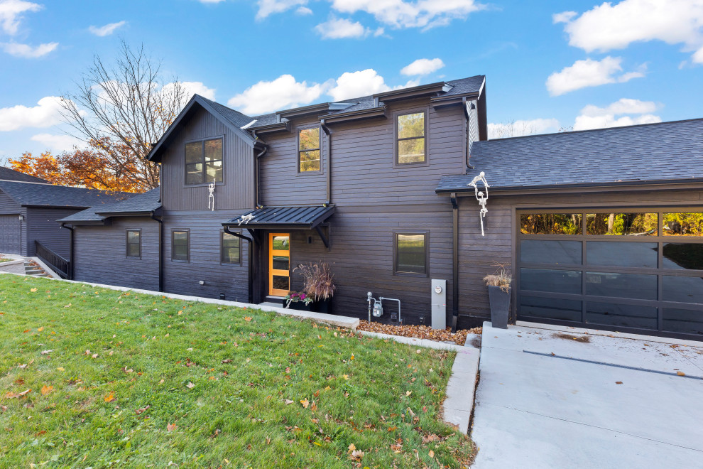 Photo of a large transitional two-storey black house exterior in Milwaukee with a gable roof, a black roof, clapboard siding and a mixed roof.