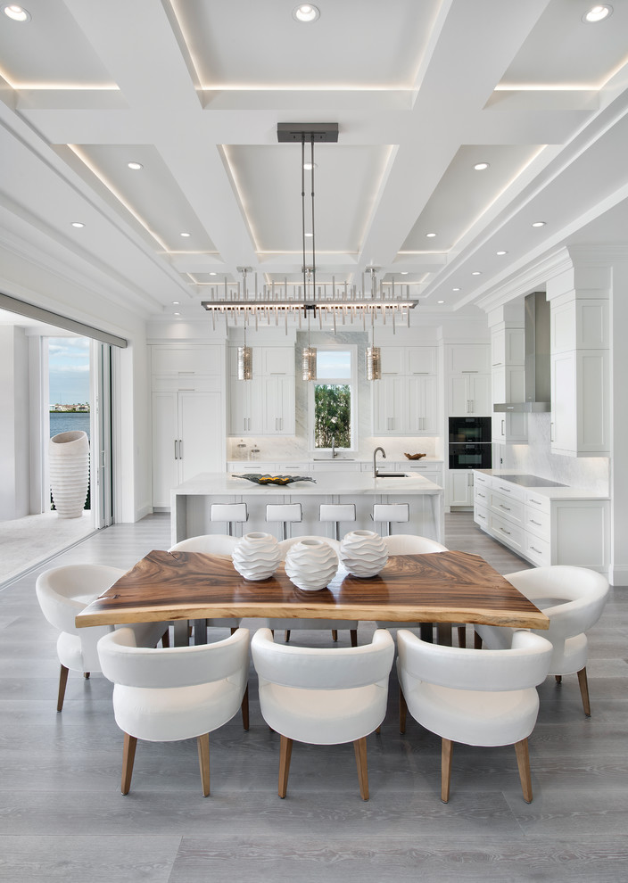 This is an example of a contemporary kitchen/dining combo in Miami with white walls and grey floor.