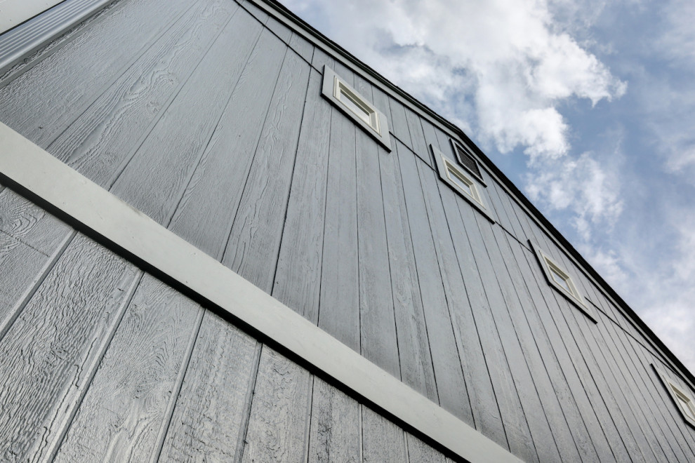 На фото: двухэтажный, серый частный загородный дом среднего размера в стиле неоклассика (современная классика) с облицовкой из ЦСП, плоской крышей, крышей из гибкой черепицы, черной крышей и отделкой планкеном с