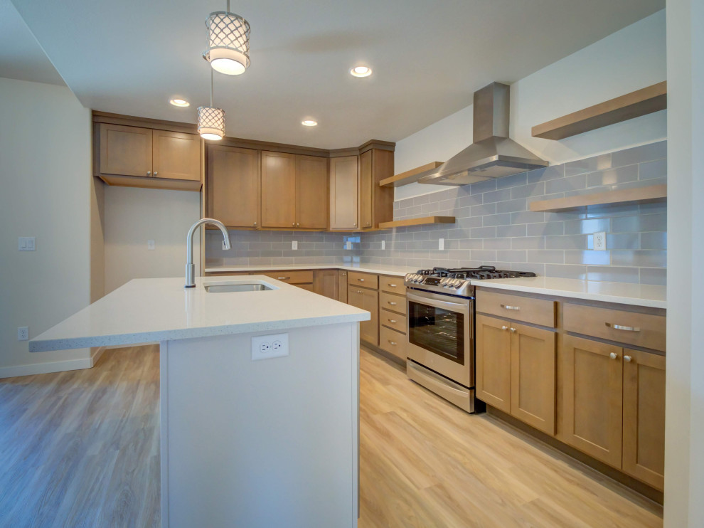 Example of a transitional l-shaped vinyl floor and beige floor eat-in kitchen design with a single-bowl sink, shaker cabinets, medium tone wood cabinets, quartz countertops, gray backsplash, ceramic backsplash, stainless steel appliances, an island and white countertops