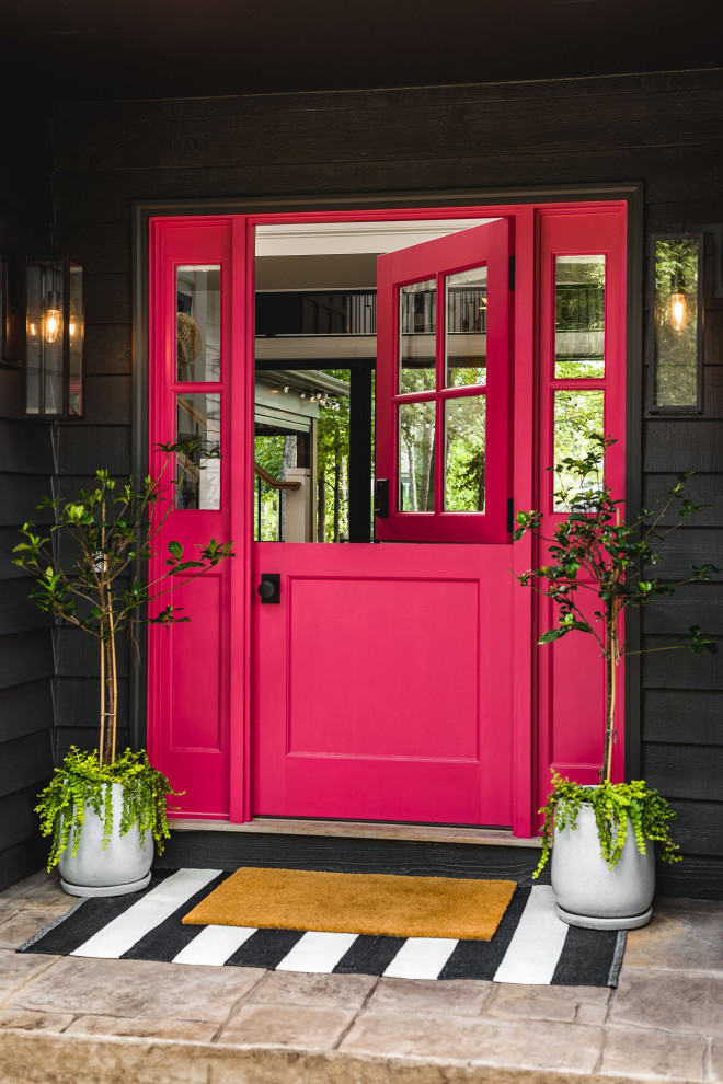 На фото: входная дверь среднего размера в морском стиле с черными стенами, бетонным полом, голландской входной дверью, красной входной дверью, бежевым полом и стенами из вагонки с