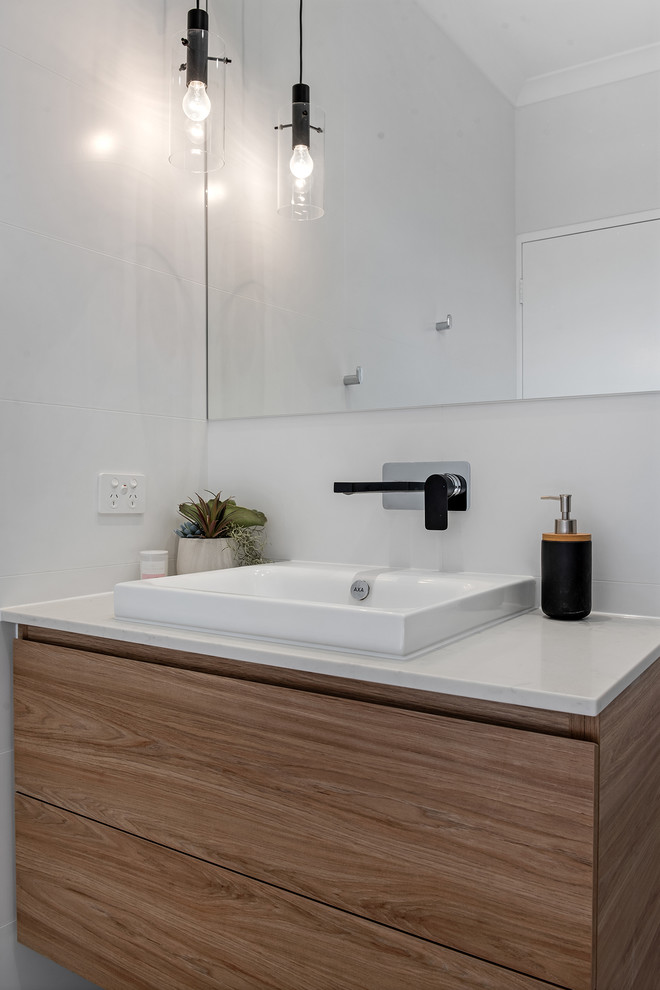 This is an example of a small modern kids bathroom in Perth with flat-panel cabinets, medium wood cabinets, a corner tub, an open shower, white tile, porcelain tile, a drop-in sink, engineered quartz benchtops, an open shower and white benchtops.