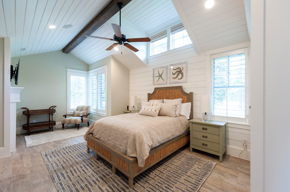 Mid-sized beach style master bedroom in Houston with white walls, light hardwood floors, a standard fireplace, brown floor, timber and planked wall panelling.