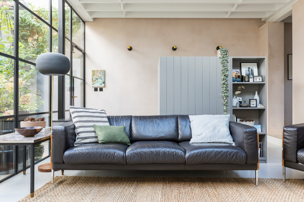 This is an example of an industrial living room in London with concrete floors, grey floor and pink walls.