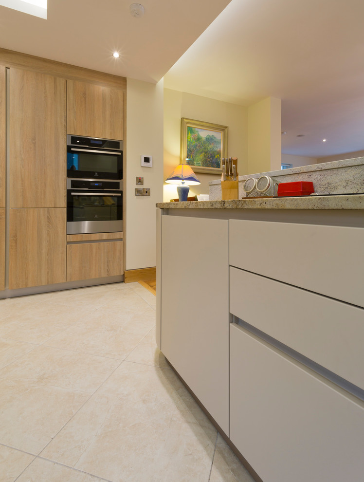 Photo of a mid-sized contemporary u-shaped eat-in kitchen in Dublin with an undermount sink, flat-panel cabinets, beige cabinets, granite benchtops and no island.