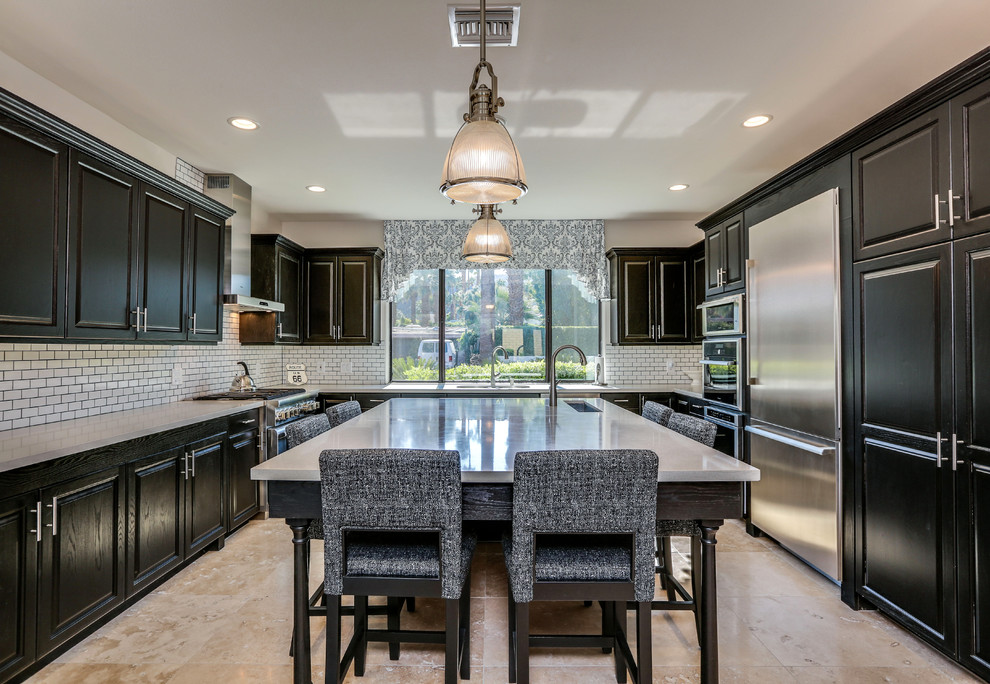 Eat-in kitchen - mid-sized transitional u-shaped travertine floor and brown floor eat-in kitchen idea with an undermount sink, raised-panel cabinets, black cabinets, quartz countertops, white backsplash, subway tile backsplash, stainless steel appliances, an island and gray countertops