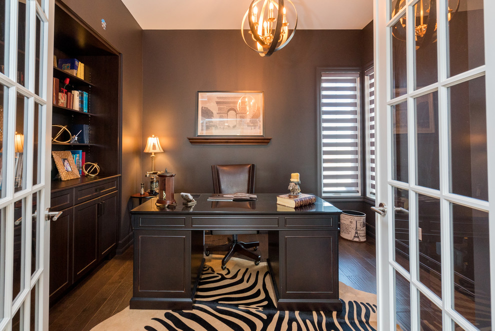 Transitional home office in Other with black walls, dark hardwood floors, a freestanding desk and brown floor.