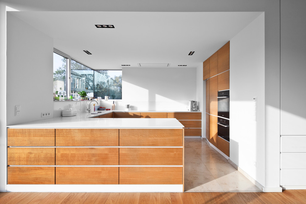 Photo of a large contemporary u-shaped separate kitchen in Cologne with flat-panel cabinets, medium wood cabinets, white splashback, glass sheet splashback, black appliances, travertine floors and a peninsula.