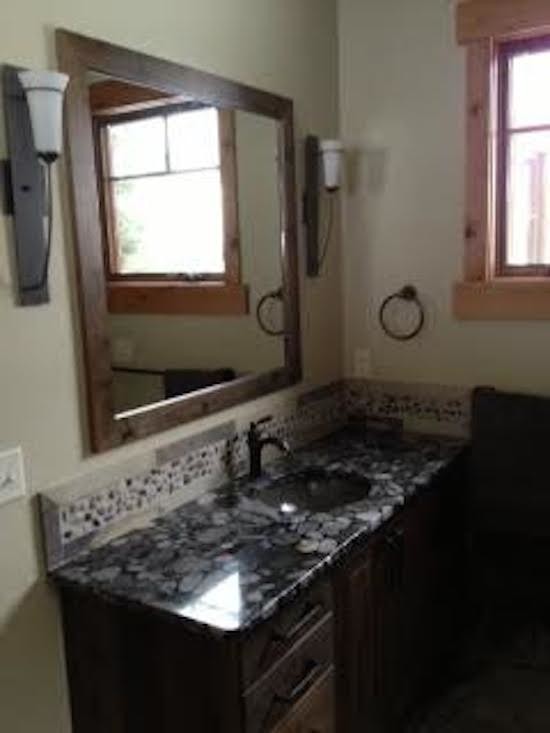 Beige tile and stone tile bathroom photo in Boise with a drop-in sink, raised-panel cabinets, dark wood cabinets and beige walls