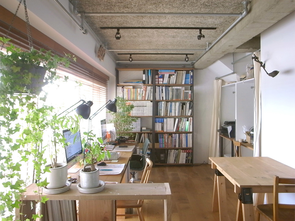 Photo of a scandinavian home studio with white walls and medium hardwood floors.