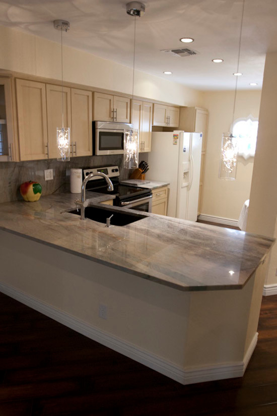 Enclosed kitchen - mid-sized transitional l-shaped dark wood floor and brown floor enclosed kitchen idea in Phoenix with an undermount sink, shaker cabinets, light wood cabinets, granite countertops, beige backsplash, stone slab backsplash, stainless steel appliances and a peninsula