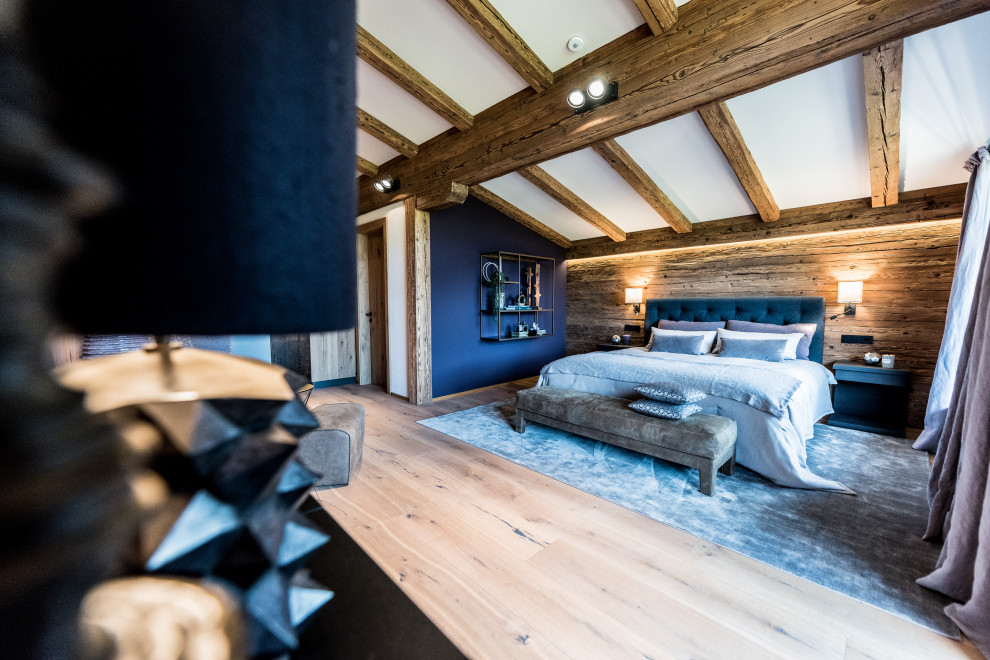 Immagine di una grande e In mansarda camera degli ospiti design con pareti viola, pavimento in legno massello medio, travi a vista e pareti in legno