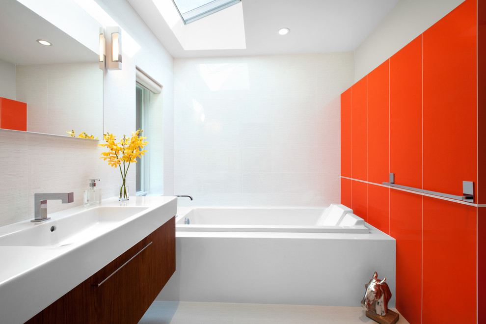 Photo of a mid-sized midcentury master bathroom in Vancouver with an integrated sink, a drop-in tub, flat-panel cabinets, medium wood cabinets, porcelain floors, red walls, white tile, engineered quartz benchtops and grey floor.