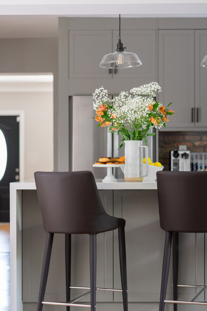 Example of a mid-sized transitional galley medium tone wood floor eat-in kitchen design in Miami with an undermount sink, shaker cabinets, gray cabinets, quartz countertops, white backsplash, subway tile backsplash, stainless steel appliances, a peninsula and white countertops