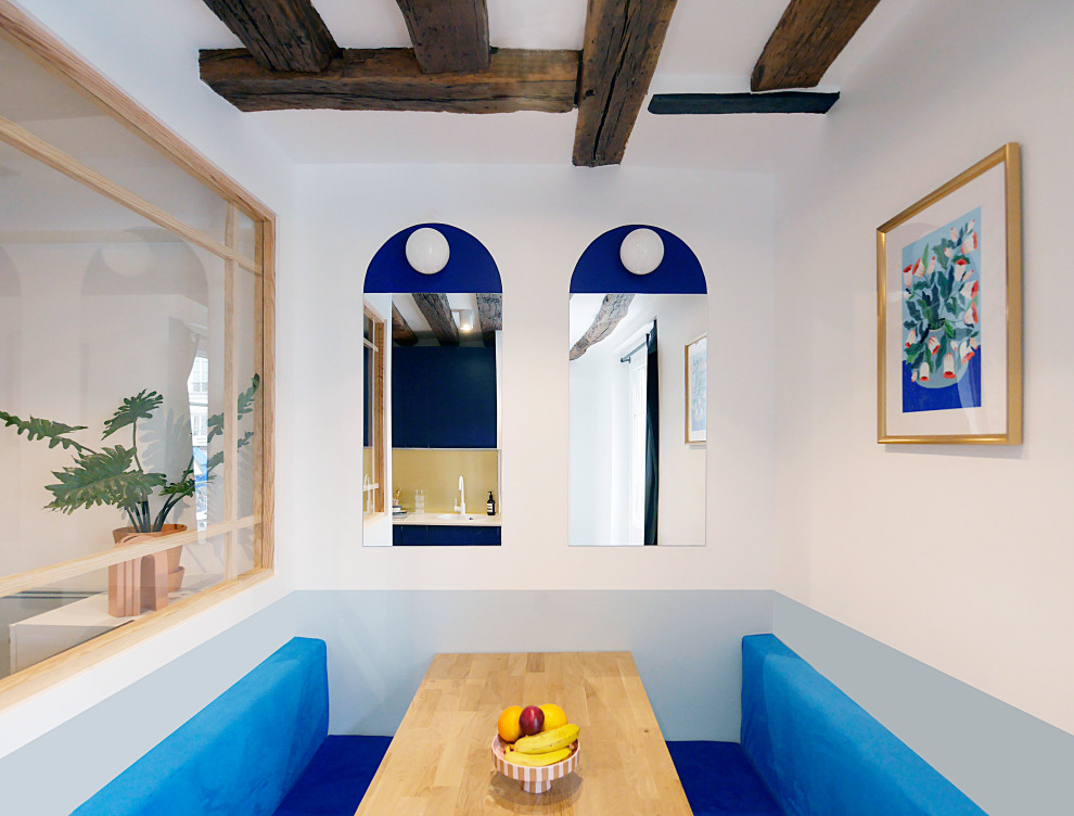 Small modern dining room with blue walls, light hardwood floors, beige floor and exposed beam.