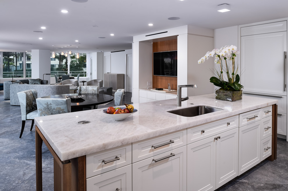 Large transitional l-shaped eat-in kitchen in Miami with flat-panel cabinets, medium wood cabinets, marble benchtops, panelled appliances, marble floors, with island and an undermount sink.