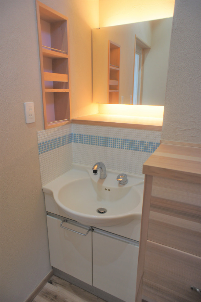 他の地域にある広いトラディショナルスタイルのおしゃれなトイレ・洗面所 (フラットパネル扉のキャビネット、白いキャビネット、白いタイル、モザイクタイル、無垢フローリング、アンダーカウンター洗面器、人工大理石カウンター、茶色い床、白い洗面カウンター、造り付け洗面台) の写真