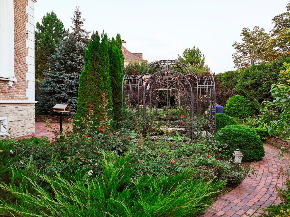 Foto di un giardino vittoriano esposto in pieno sole di medie dimensioni e davanti casa in autunno con pavimentazioni in mattoni e recinzione in legno