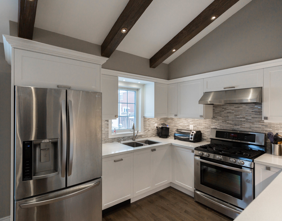 Example of a mid-sized transitional u-shaped medium tone wood floor and brown floor open concept kitchen design in Toronto with a double-bowl sink, recessed-panel cabinets, white cabinets, quartz countertops, gray backsplash, marble backsplash, stainless steel appliances, no island and white countertops