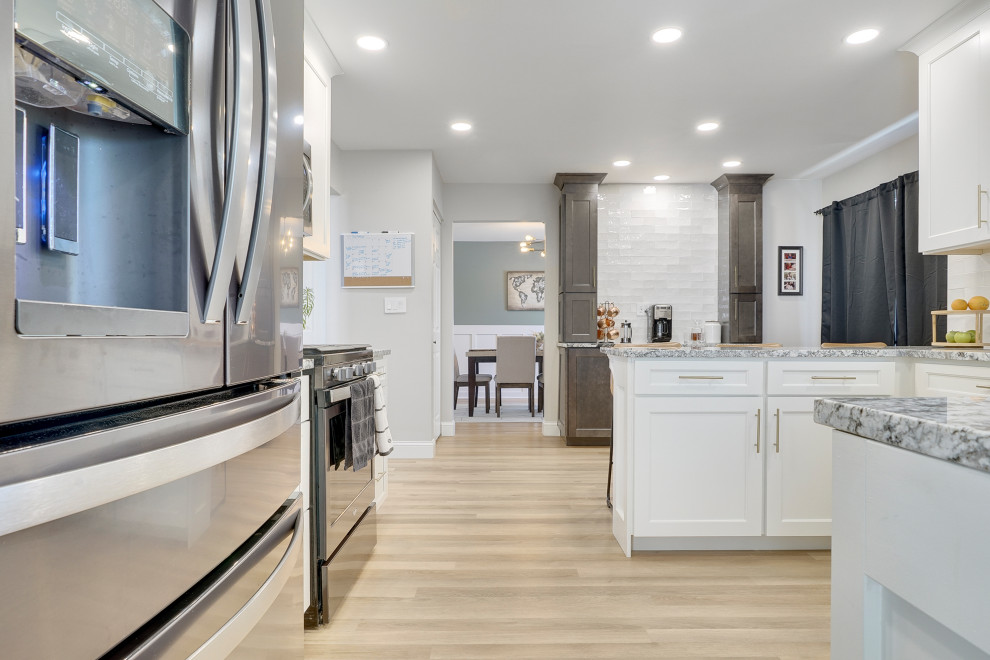 Design ideas for a mid-sized transitional u-shaped open plan kitchen in Chicago with a single-bowl sink, beaded inset cabinets, white cabinets, marble benchtops, white splashback, ceramic splashback, stainless steel appliances, vinyl floors, a peninsula, beige floor and grey benchtop.