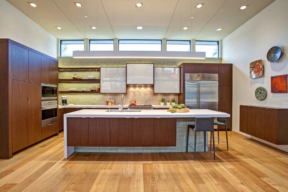 This is an example of a contemporary u-shaped kitchen in San Diego with an undermount sink, flat-panel cabinets, dark wood cabinets, green splashback and stainless steel appliances.