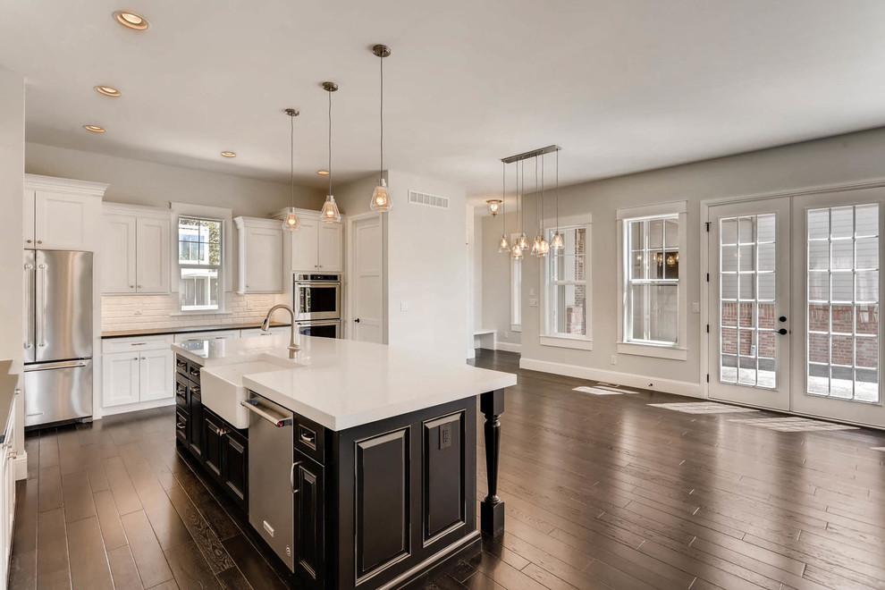 Open concept kitchen - large transitional l-shaped dark wood floor and brown floor open concept kitchen idea in Denver with recessed-panel cabinets, white cabinets, ceramic backsplash, stainless steel appliances and an island