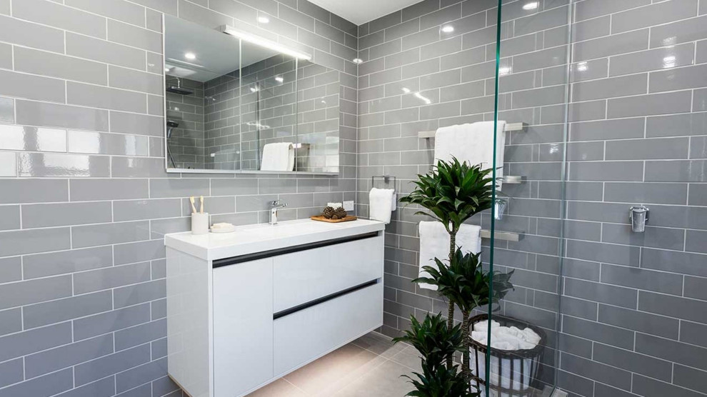 This is an example of a large country kids bathroom in London with flat-panel cabinets, white cabinets, a freestanding tub, a corner shower, a two-piece toilet, gray tile, ceramic tile, grey walls, porcelain floors, an integrated sink, solid surface benchtops, grey floor, a sliding shower screen, white benchtops, a single vanity and a floating vanity.