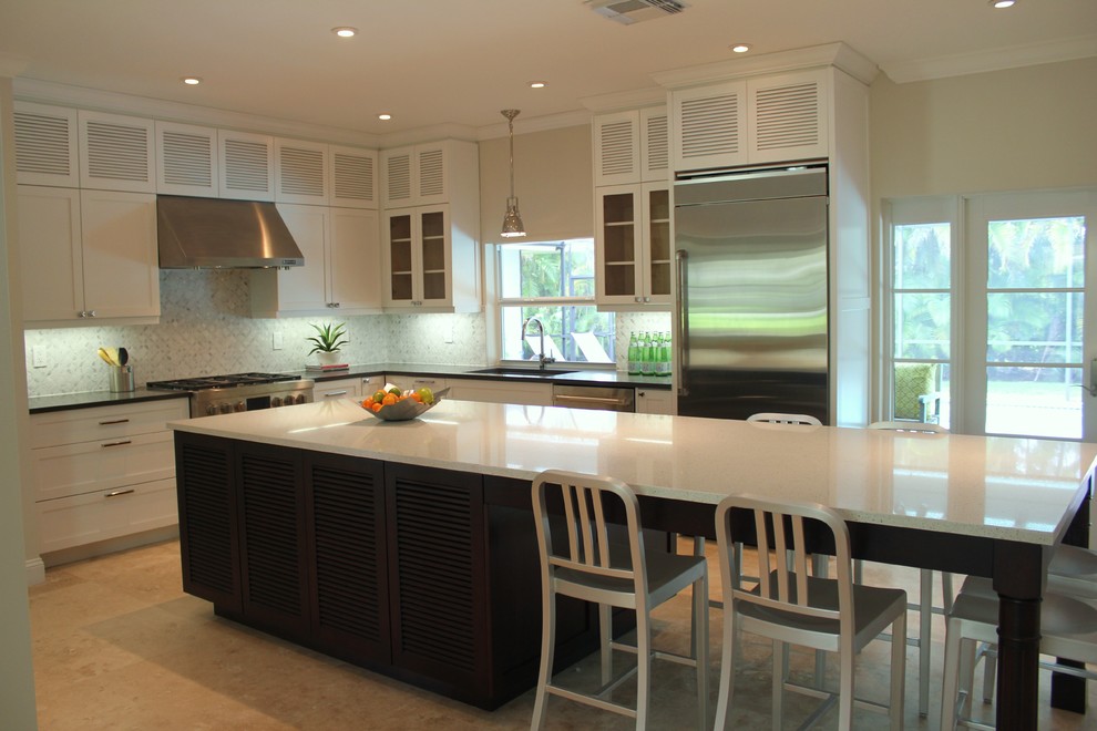 Photo of a contemporary l-shaped kitchen in Miami with mosaic tile splashback, stainless steel appliances, recessed-panel cabinets, white cabinets and white splashback.