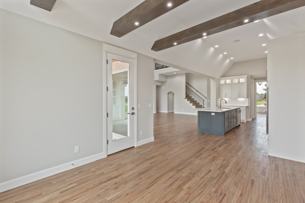 Transitional galley light wood floor and brown floor eat-in kitchen photo with an undermount sink, shaker cabinets, white cabinets, quartzite countertops, white backsplash, quartz backsplash, stainless steel appliances, an island and white countertops