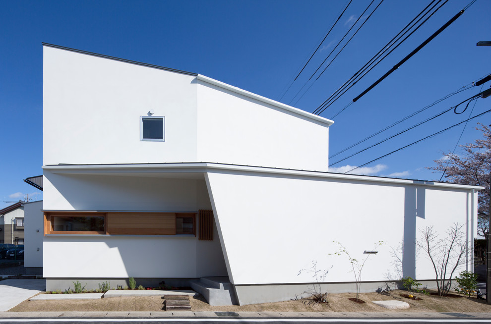 This is an example of a mid-sized modern two-storey stucco white house exterior in Nagoya with a shed roof and a metal roof.