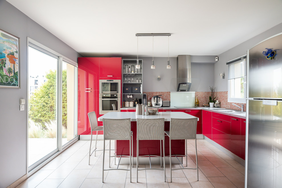 Photo of a large contemporary l-shaped kitchen in Paris with a double-bowl sink, flat-panel cabinets, red cabinets, laminate benchtops, red splashback, mosaic tile splashback, stainless steel appliances, with island, beige floor and grey benchtop.