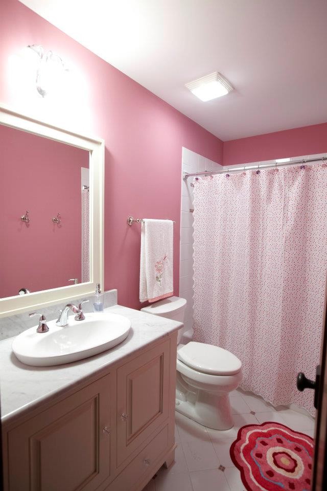 Inspiration for a mid-sized traditional kids bathroom in Chicago with a shower/bathtub combo, a one-piece toilet, white tile, pink walls, raised-panel cabinets, white cabinets, an alcove tub and ceramic floors.