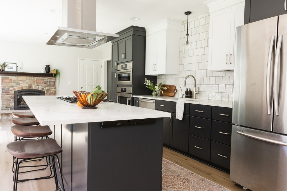 Eat-in kitchen - mid-sized transitional galley vinyl floor and brown floor eat-in kitchen idea with an undermount sink, shaker cabinets, black cabinets, quartz countertops, white backsplash, stainless steel appliances, an island and white countertops