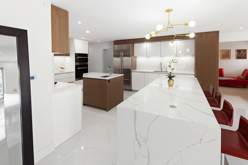 This is an example of a large contemporary u-shaped eat-in kitchen in New York with an undermount sink, flat-panel cabinets, medium wood cabinets, quartz benchtops, white splashback, engineered quartz splashback, stainless steel appliances, porcelain floors, multiple islands, white floor and white benchtop.