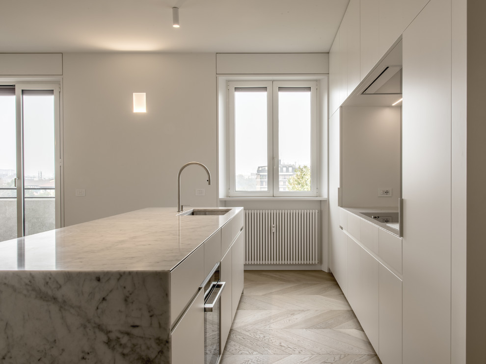 Design ideas for an expansive modern open plan kitchen in Milan with an undermount sink, flat-panel cabinets, white cabinets, marble benchtops, grey splashback, glass sheet splashback, stainless steel appliances and with island.