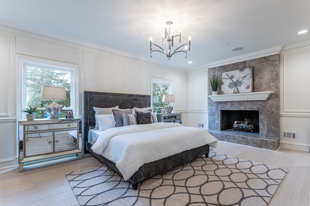 Design ideas for a traditional master bedroom in Atlanta with white walls, light hardwood floors, a standard fireplace, a tile fireplace surround, beige floor and panelled walls.