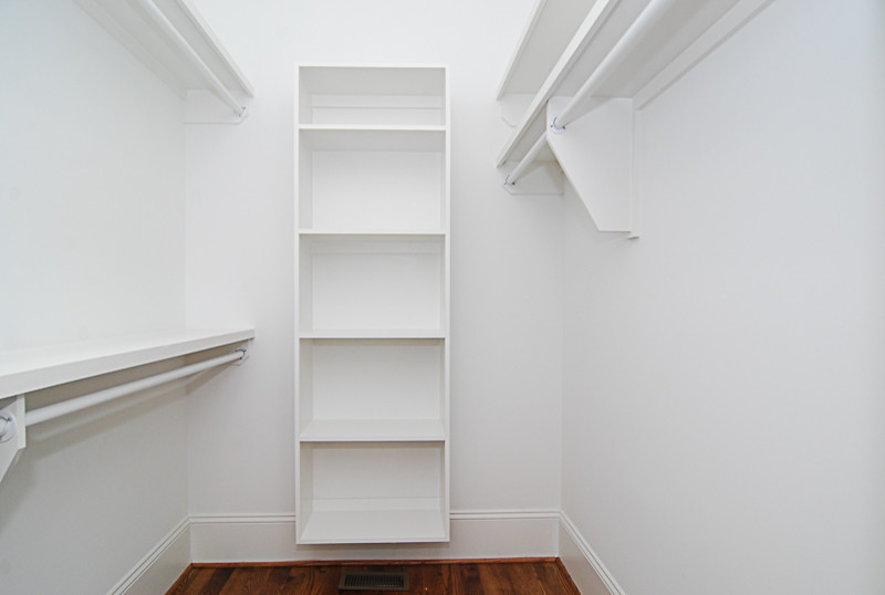 This is an example of a mid-sized traditional gender-neutral walk-in wardrobe in Other with open cabinets, white cabinets, medium hardwood floors and brown floor.